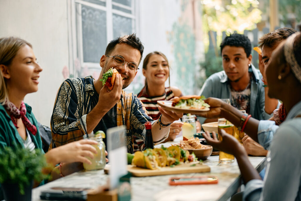 Group of people enjoying a meal and passing a plate of tacos