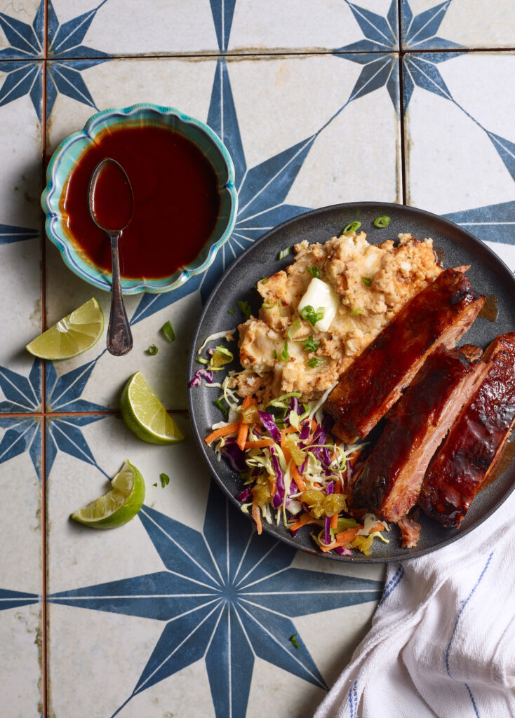 Overhead shot of honey guajillo glazed pork ribs with chipotle mashed potatoes on a patterned table top