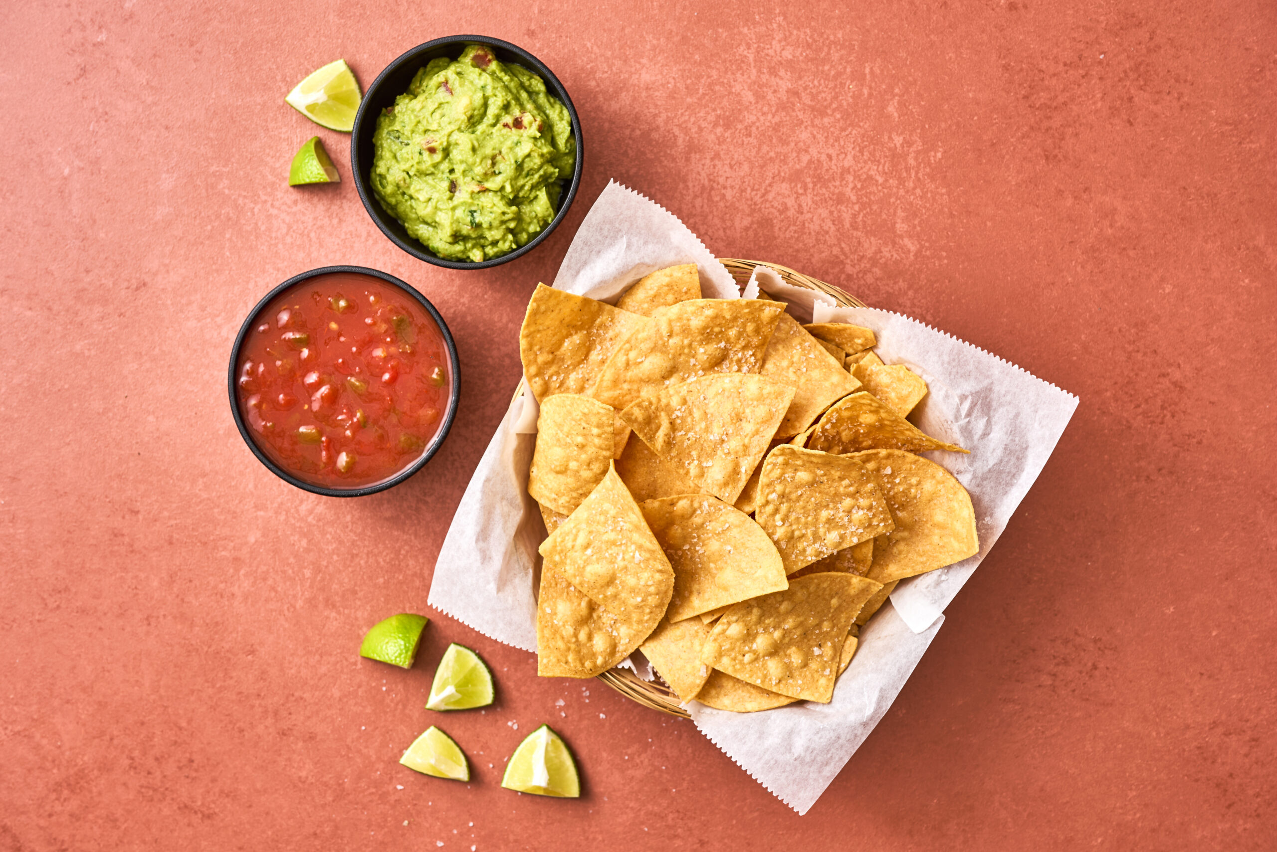 Top down shot of chips and Embasa Salsa Roja. Guacamole and lime also included.